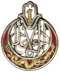 La devise du 1er Régiment de tirailleurs d’Algérie, « Toujours le Premier », inscrite en caractères arabes.